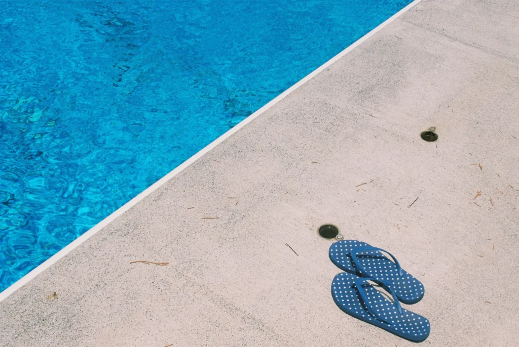 Flip-flops next to a swimming pool